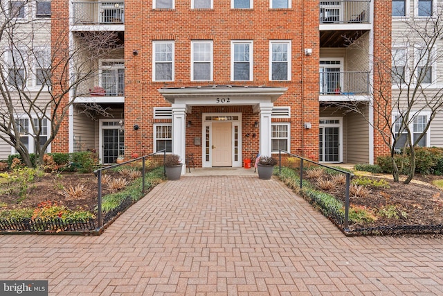 view of front of house with fence, decorative driveway, and brick siding