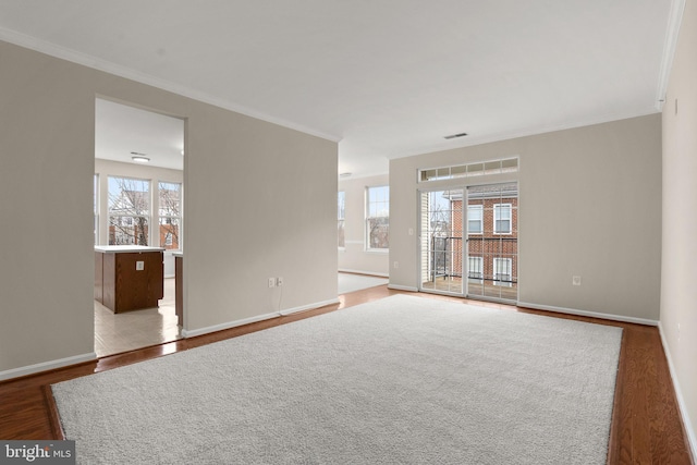 unfurnished room featuring crown molding, baseboards, and wood finished floors