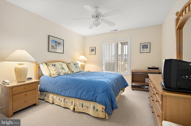 bedroom featuring ceiling fan, light colored carpet, and a textured ceiling