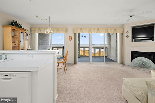 interior space with hanging light fixtures, dishwasher, a fireplace, and light colored carpet