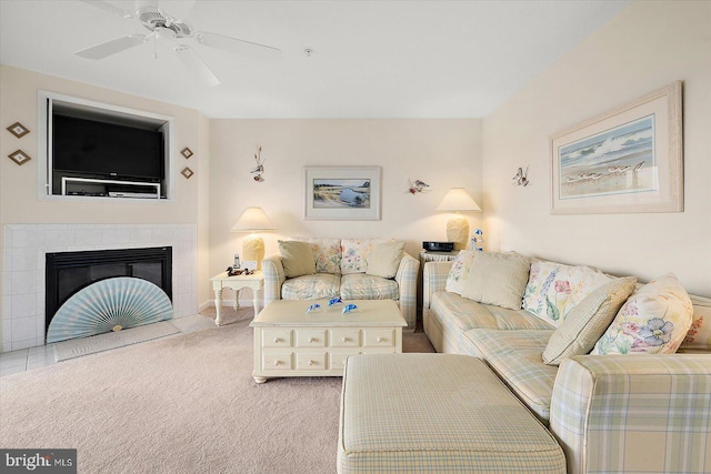 living room featuring carpet flooring, a tiled fireplace, and ceiling fan