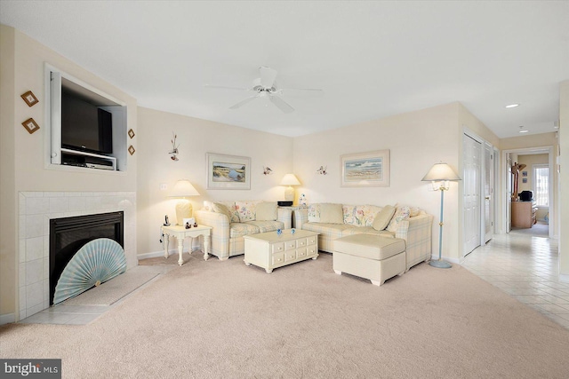 carpeted living room with a tiled fireplace and ceiling fan