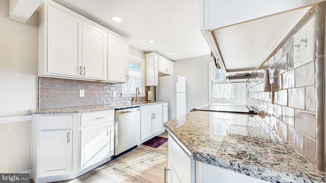 kitchen featuring dishwasher, light stone countertops, white cabinetry, and decorative backsplash