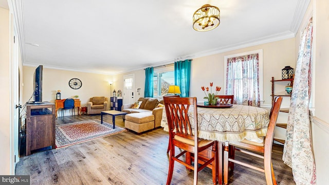 dining area featuring an inviting chandelier, ornamental molding, and hardwood / wood-style flooring