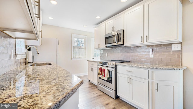 kitchen featuring sink, stainless steel appliances, white cabinetry, and light stone counters