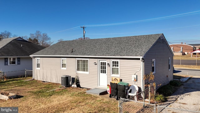 rear view of property with a yard and central air condition unit