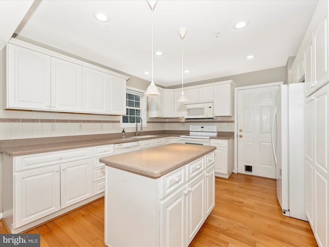 kitchen featuring pendant lighting, white appliances, light wood-type flooring, a kitchen island, and white cabinetry