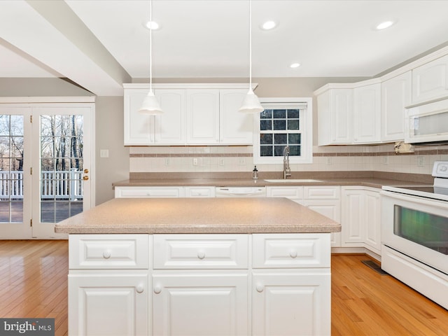 kitchen with white appliances, sink, hanging light fixtures, decorative backsplash, and light hardwood / wood-style floors