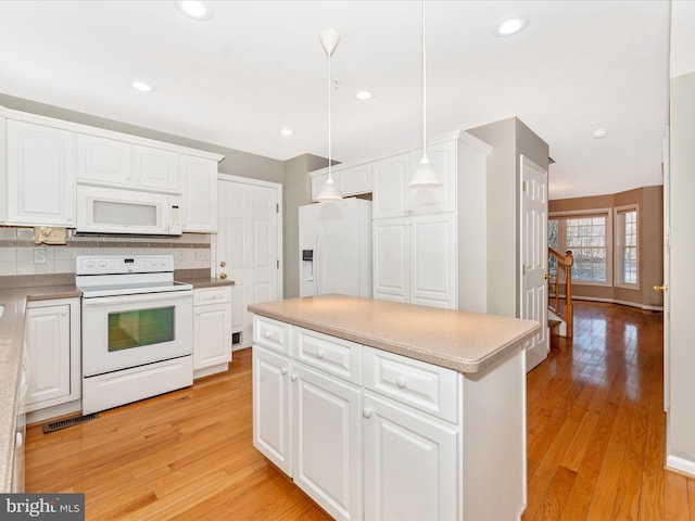 kitchen featuring pendant lighting, white appliances, light hardwood / wood-style floors, and white cabinetry