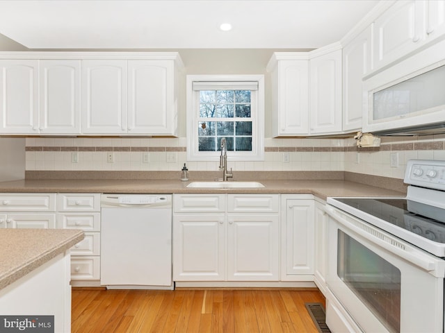 kitchen with white appliances, white cabinets, sink, decorative backsplash, and light hardwood / wood-style floors