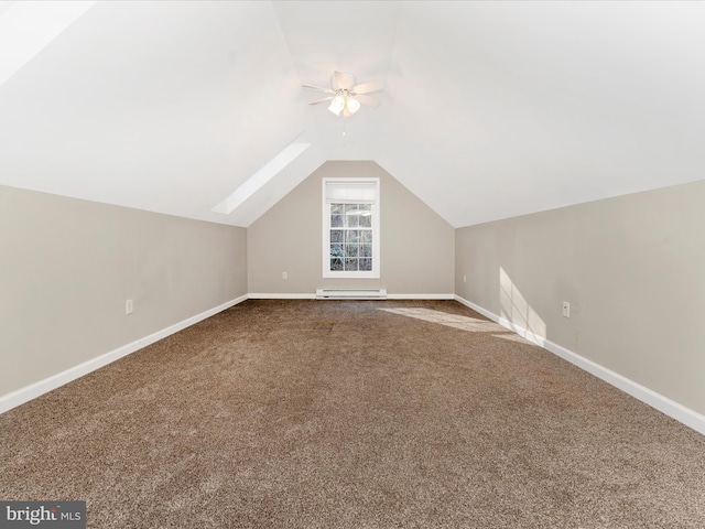 additional living space with vaulted ceiling with skylight, carpet flooring, ceiling fan, and a baseboard radiator