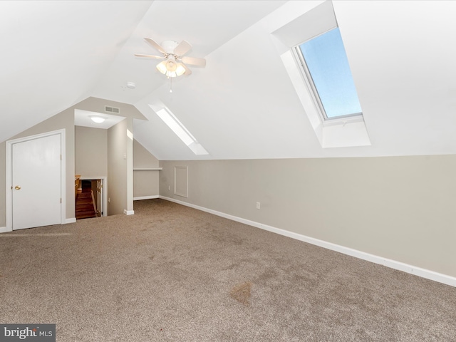 additional living space with carpet, lofted ceiling with skylight, and ceiling fan