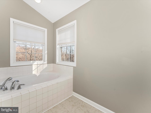 bathroom featuring tiled bath and vaulted ceiling