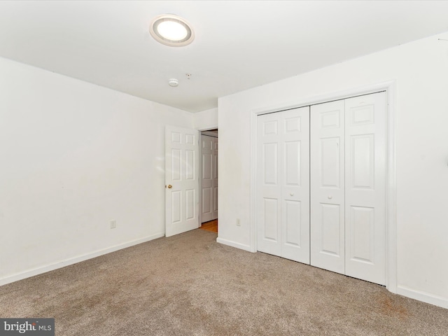 unfurnished bedroom featuring light carpet and a closet