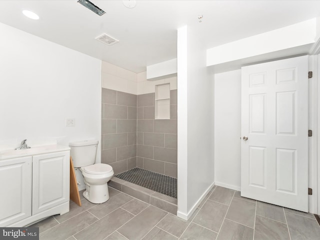 bathroom with vanity, toilet, and tiled shower