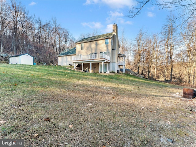 rear view of house with a yard, a deck, and a storage unit