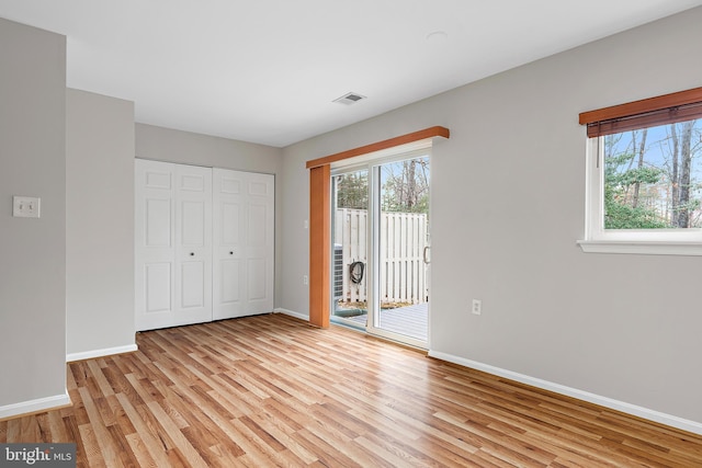 unfurnished bedroom featuring a closet, access to exterior, and light hardwood / wood-style flooring