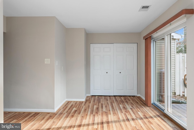 unfurnished bedroom featuring access to exterior, light wood-type flooring, and a closet