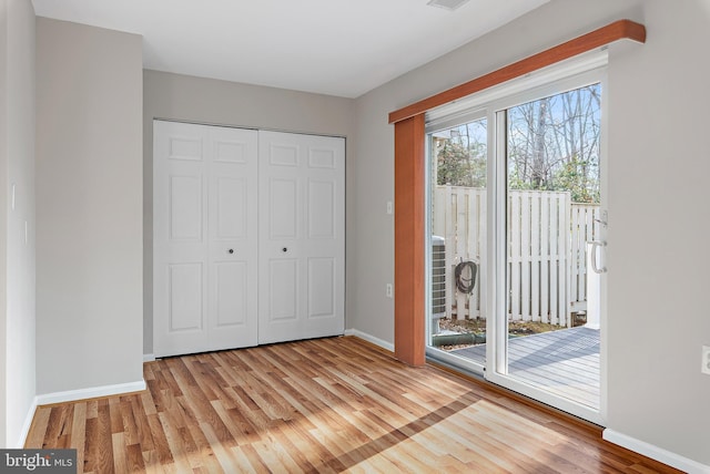 unfurnished bedroom with access to outside, a closet, and light hardwood / wood-style flooring