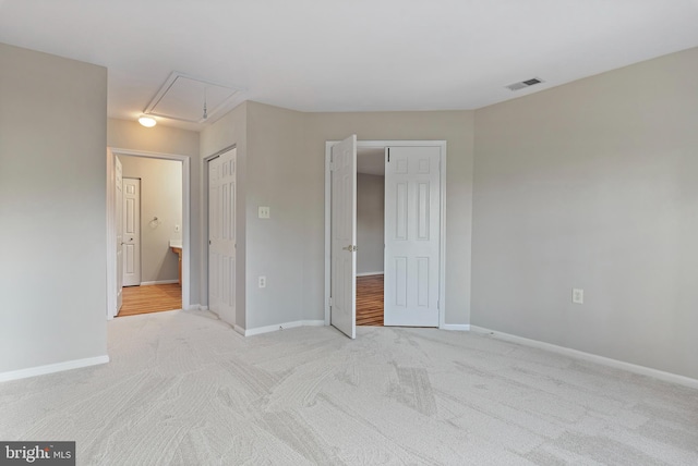 unfurnished bedroom with ensuite bath and light colored carpet