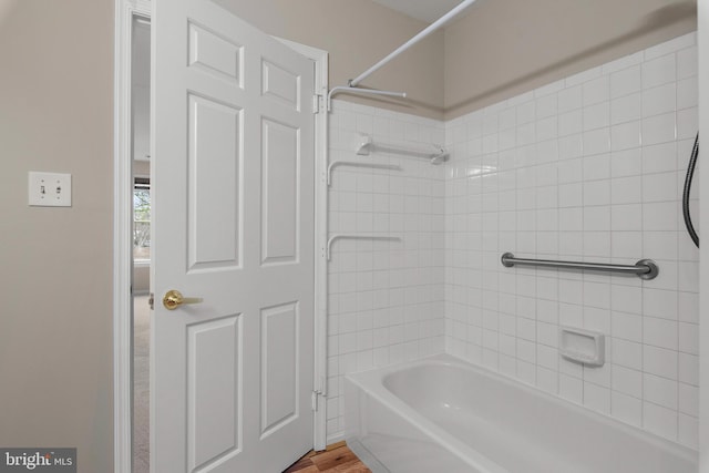 bathroom with hardwood / wood-style floors and tiled shower / bath