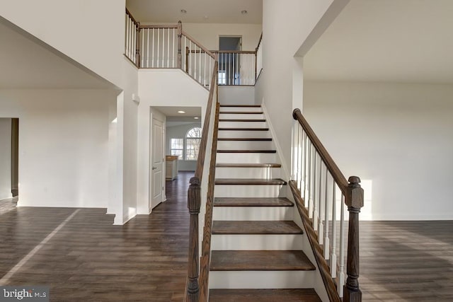 staircase featuring hardwood / wood-style floors and a high ceiling