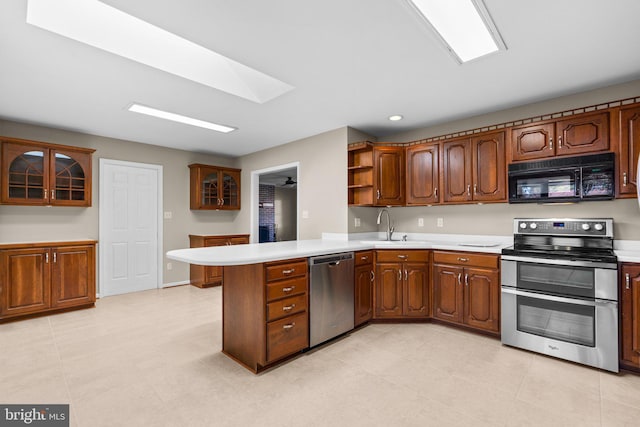 kitchen featuring kitchen peninsula, sink, a skylight, and appliances with stainless steel finishes