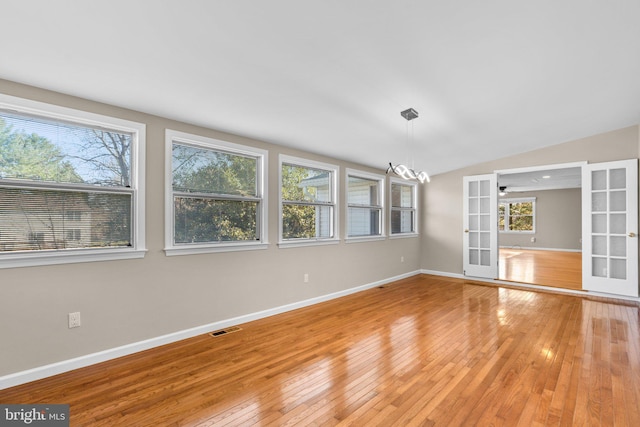 empty room featuring french doors, a healthy amount of sunlight, and wood-type flooring