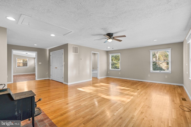 living room with ceiling fan, light wood-type flooring, and a textured ceiling