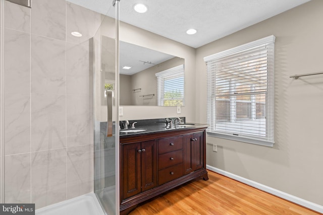 bathroom with wood-type flooring, vanity, a textured ceiling, and a tile shower