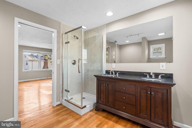 bathroom featuring vanity, hardwood / wood-style floors, a textured ceiling, and a shower with door