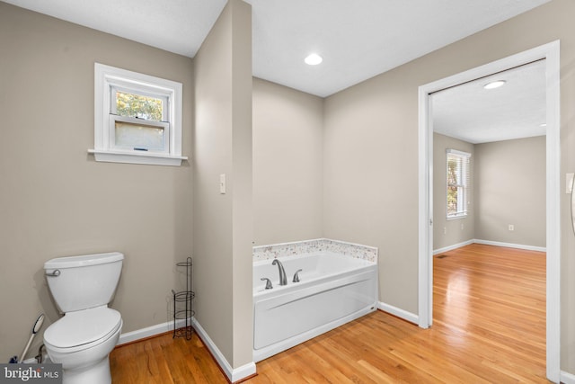 bathroom featuring wood-type flooring, toilet, and a wealth of natural light