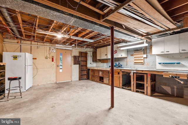 basement featuring a workshop area and white fridge