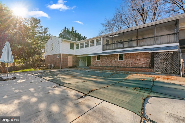 rear view of house with a patio, central air condition unit, a covered pool, and a sunroom