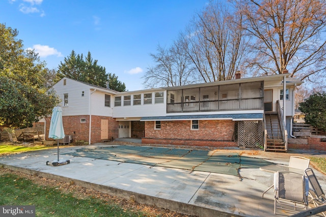 back of house with a sunroom, cooling unit, a patio, and a covered pool