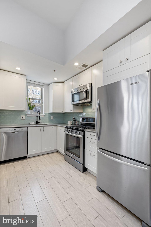 kitchen with white cabinets, backsplash, sink, and appliances with stainless steel finishes