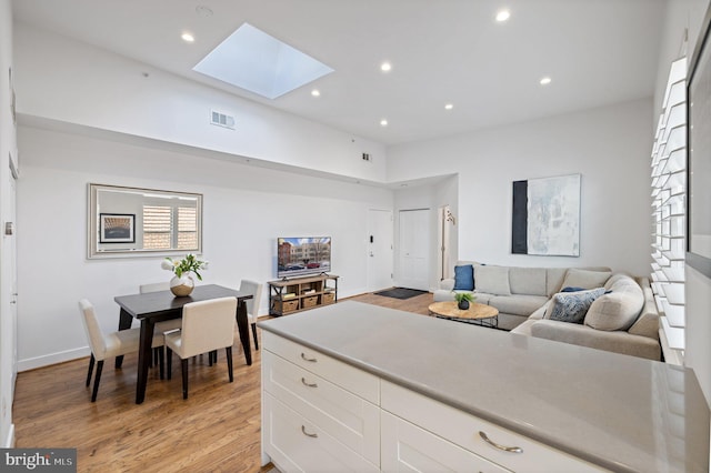 kitchen featuring a skylight, white cabinets, and light hardwood / wood-style floors