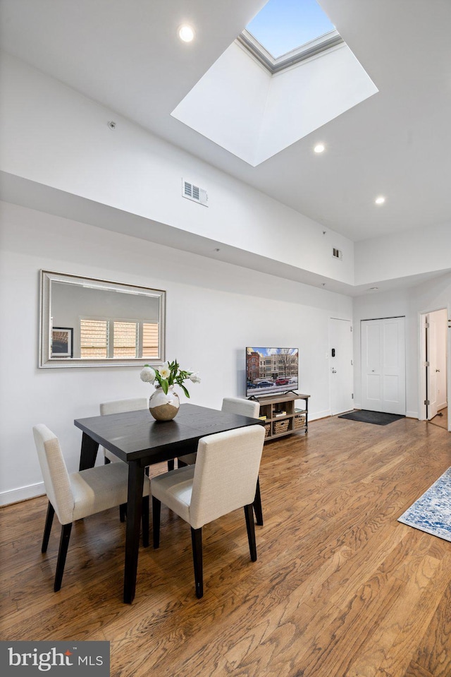 dining room featuring a skylight and wood-type flooring