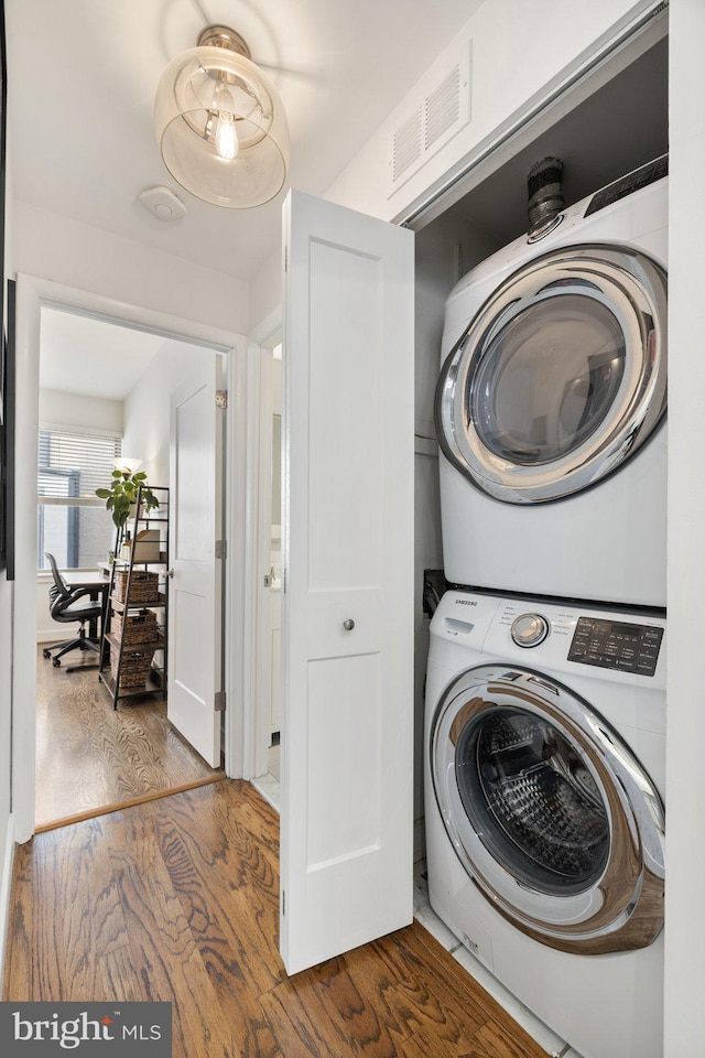 washroom with stacked washer and clothes dryer and hardwood / wood-style flooring