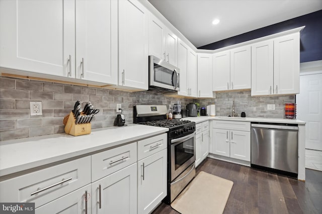 kitchen with backsplash, dark wood-type flooring, white cabinets, sink, and appliances with stainless steel finishes