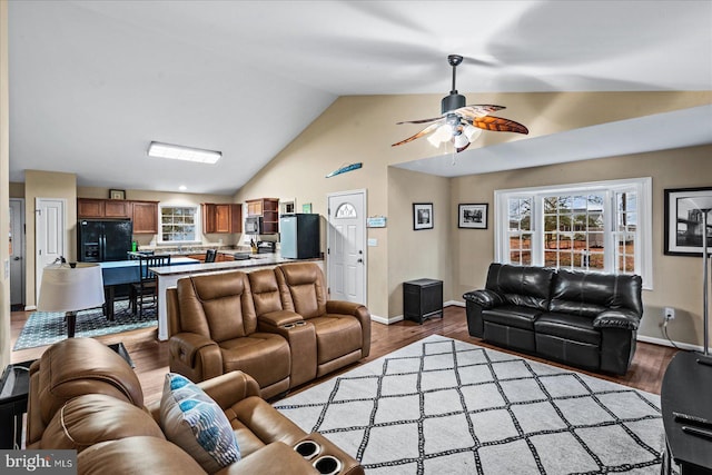 living room with ceiling fan, light wood-type flooring, and lofted ceiling