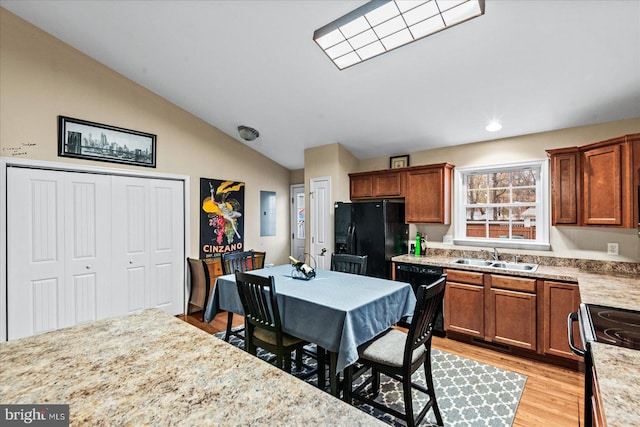 kitchen with lofted ceiling, sink, light hardwood / wood-style flooring, light stone countertops, and black fridge with ice dispenser