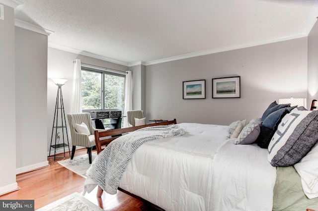 bedroom featuring a textured ceiling, wood-type flooring, and ornamental molding