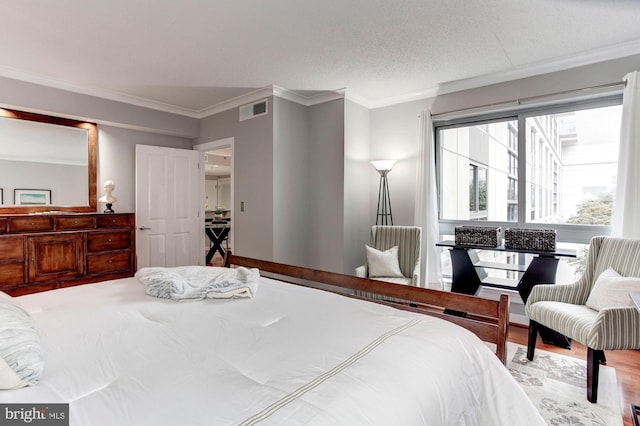 bedroom featuring crown molding, wood-type flooring, and a textured ceiling