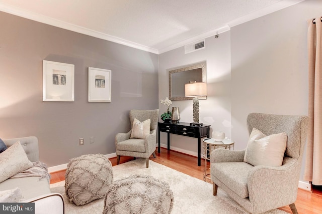 sitting room with hardwood / wood-style floors and ornamental molding