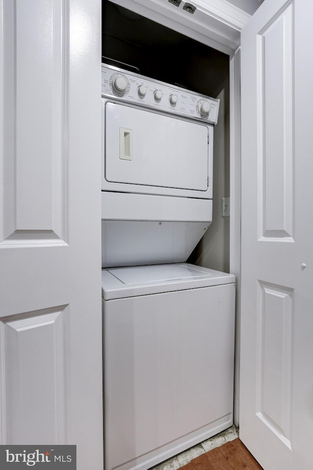 laundry room with light hardwood / wood-style flooring and stacked washing maching and dryer