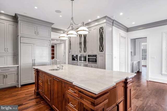 kitchen with decorative light fixtures, sink, oven, light stone countertops, and paneled refrigerator