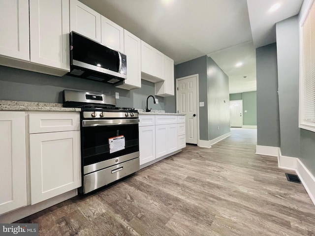 kitchen featuring white cabinetry, stainless steel appliances, and light wood-type flooring