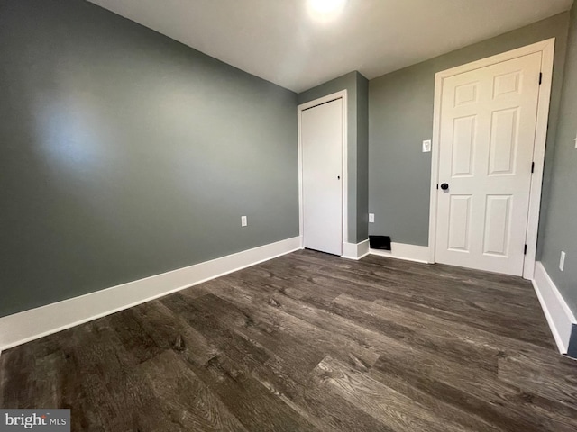 unfurnished bedroom featuring a closet and dark wood-type flooring