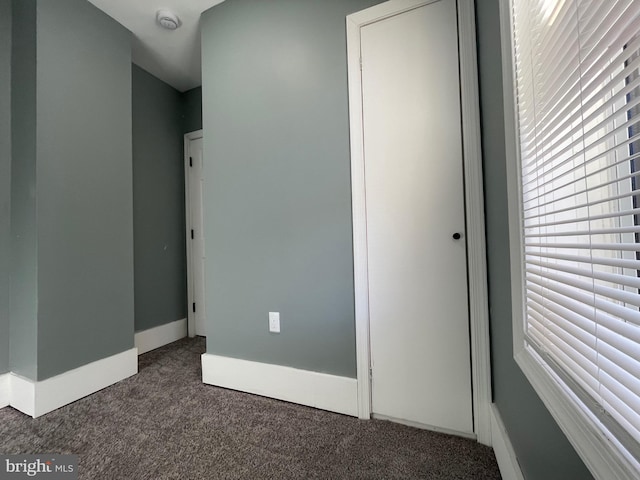 unfurnished bedroom featuring multiple windows and dark carpet